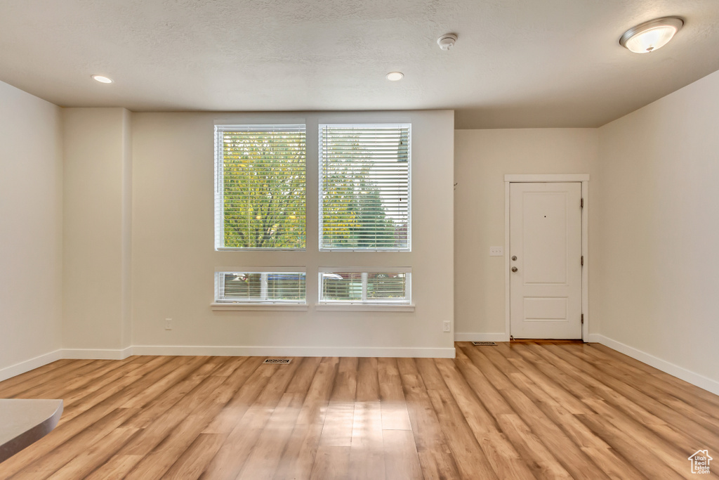 Unfurnished room with a textured ceiling and light wood-type flooring