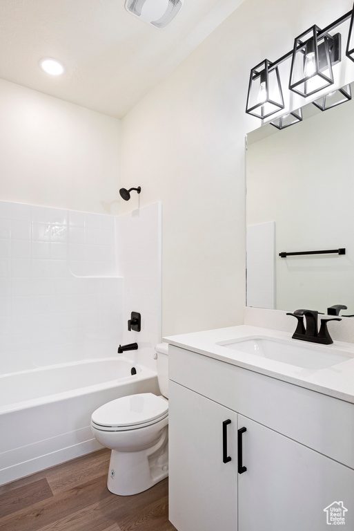 Full bathroom with toilet, vanity, wood-type flooring, and shower / bathtub combination