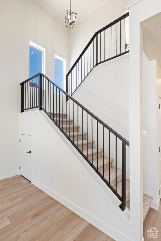 Stairs featuring a notable chandelier and wood-type flooring