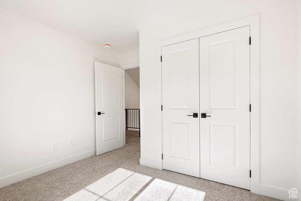 Unfurnished bedroom with light colored carpet and a closet