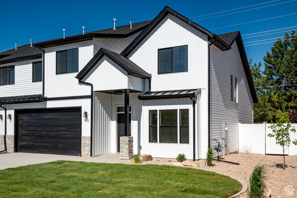 Modern farmhouse style home featuring a front yard and a garage