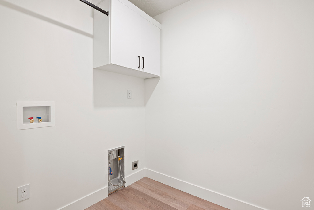 Laundry room featuring electric dryer hookup, washer hookup, light wood-type flooring, and cabinets