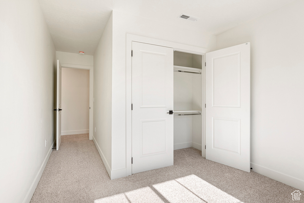 Unfurnished bedroom featuring light carpet and a closet