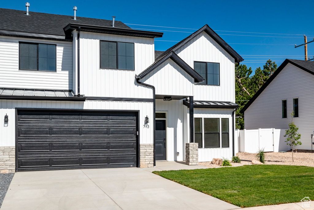 Modern farmhouse featuring a front lawn and a garage