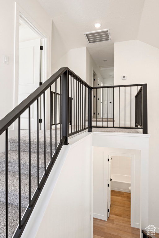 Staircase with lofted ceiling and wood-type flooring