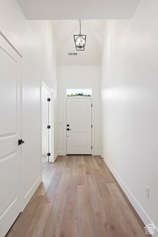 Doorway to outside featuring light hardwood / wood-style flooring and an inviting chandelier