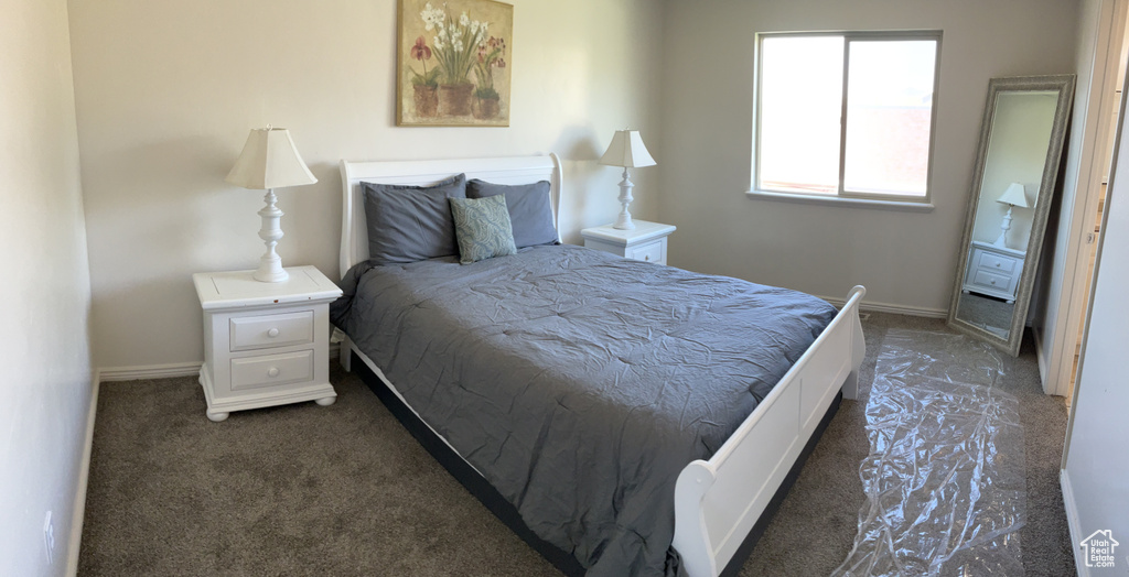 Bedroom featuring dark colored carpet and baseboards