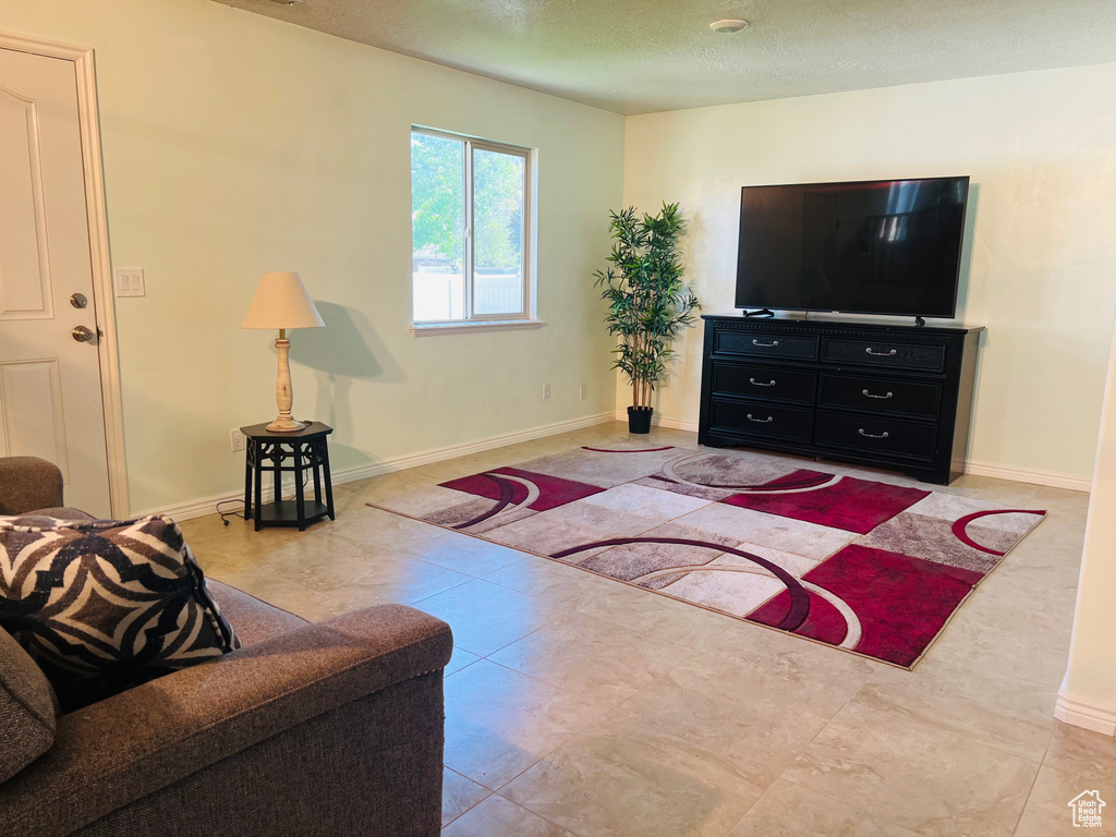 Tiled living area with baseboards and a textured ceiling