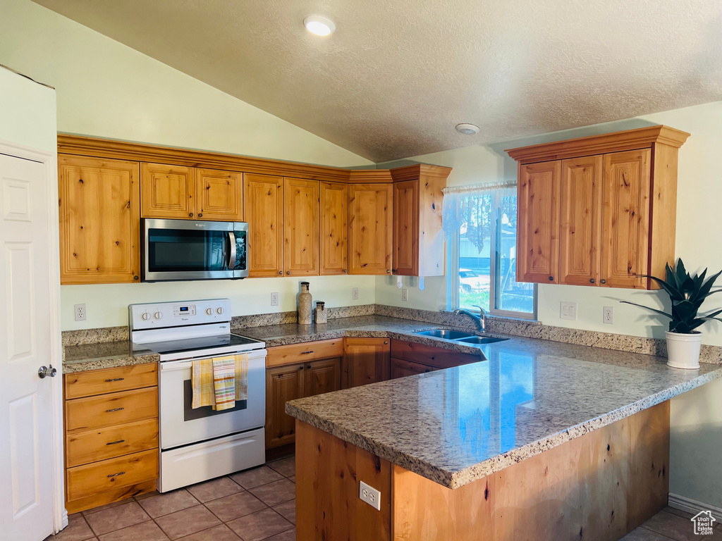 Kitchen featuring a peninsula, white electric range oven, stainless steel microwave, a sink, and vaulted ceiling