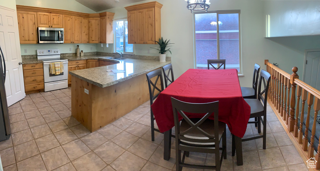 Kitchen featuring white range with electric stovetop, stainless steel microwave, a sink, a peninsula, and vaulted ceiling
