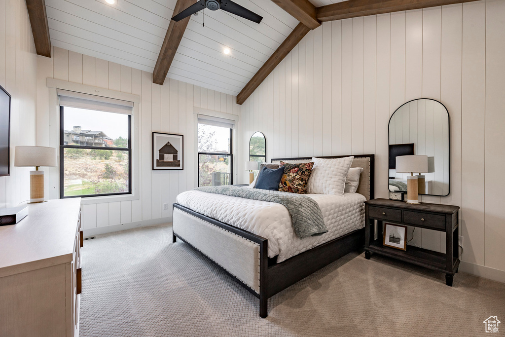 Bedroom featuring wood walls, lofted ceiling with beams, light carpet, and ceiling fan