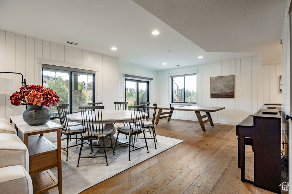 Dining area with light hardwood / wood-style floors and wooden walls