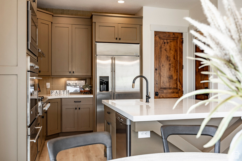 Kitchen with sink, a kitchen breakfast bar, appliances with stainless steel finishes, and tasteful backsplash