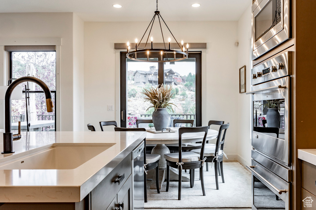 Interior space with appliances with stainless steel finishes, sink, hanging light fixtures, carpet, and a chandelier