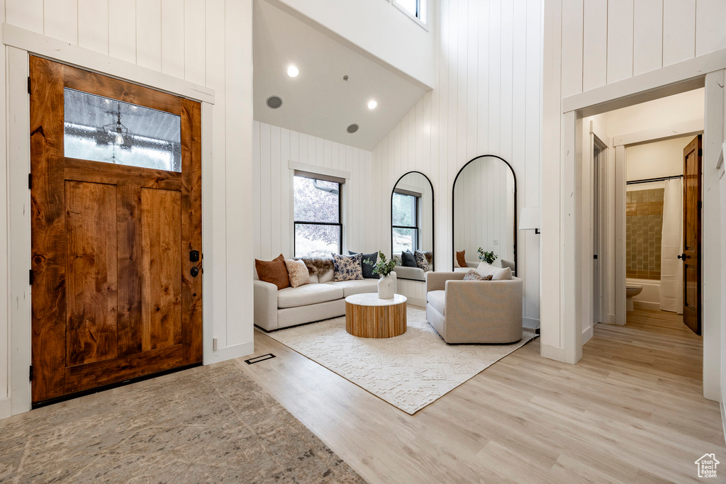 Living room featuring wooden walls, high vaulted ceiling, and light wood-type flooring