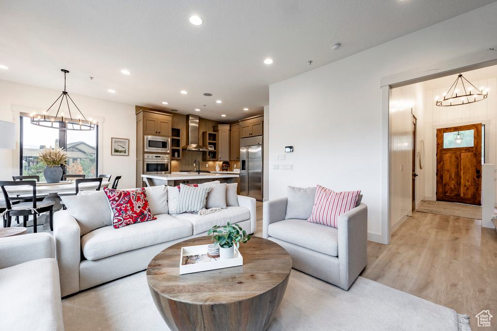 Living room with sink, an inviting chandelier, and light wood-type flooring