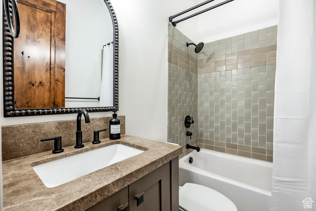 Full bathroom featuring vanity, shower / tub combo with curtain, and toilet