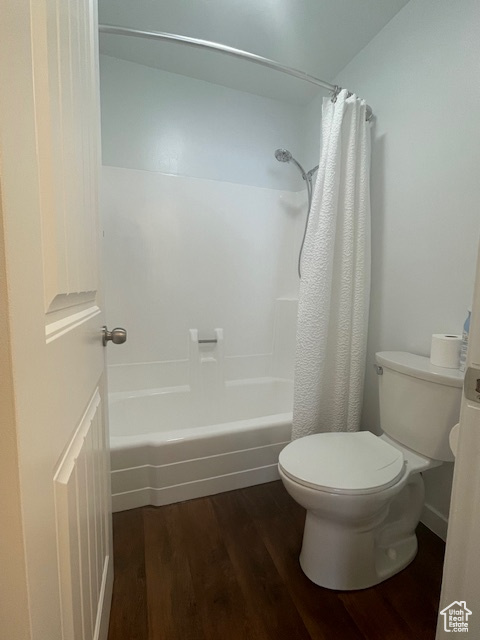 Bathroom featuring shower / bath combination with curtain, toilet, and hardwood / wood-style floors