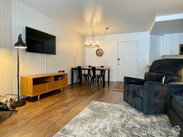 Living room featuring wooden walls, wood-type flooring, and a chandelier