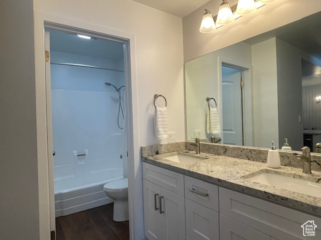 Full bathroom with vanity, toilet, shower / tub combination, and hardwood / wood-style floors