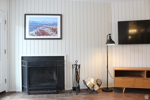 Room details with hardwood / wood-style floors, wooden walls, and a fireplace