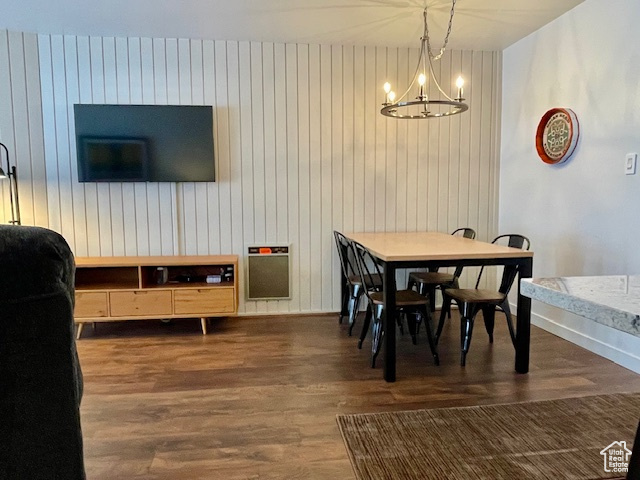 Dining room with a notable chandelier, dark hardwood / wood-style floors, and wood walls