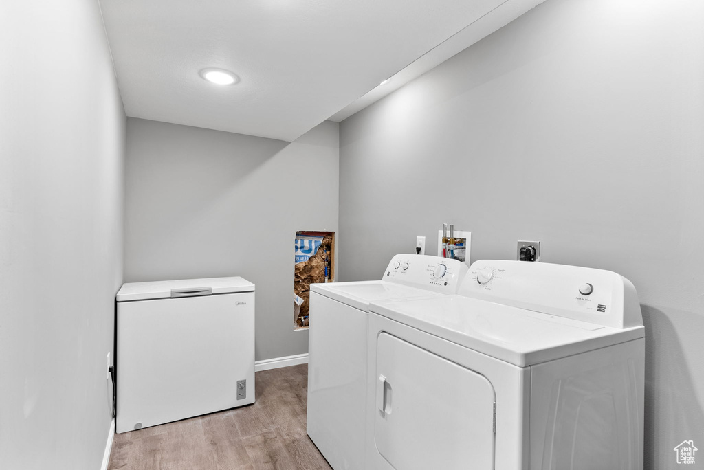 Clothes washing area with light wood-type flooring and washing machine and clothes dryer