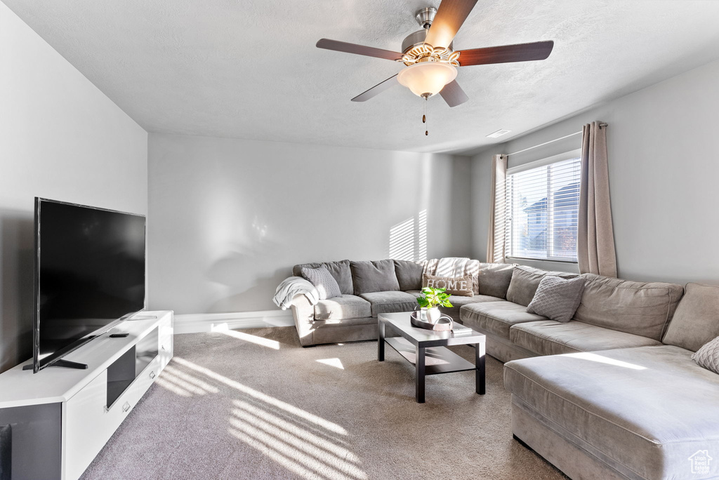 Living room featuring a textured ceiling, ceiling fan, and carpet floors