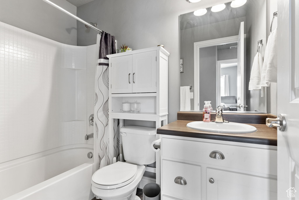 Full bathroom featuring toilet, shower / bath combo, and vanity