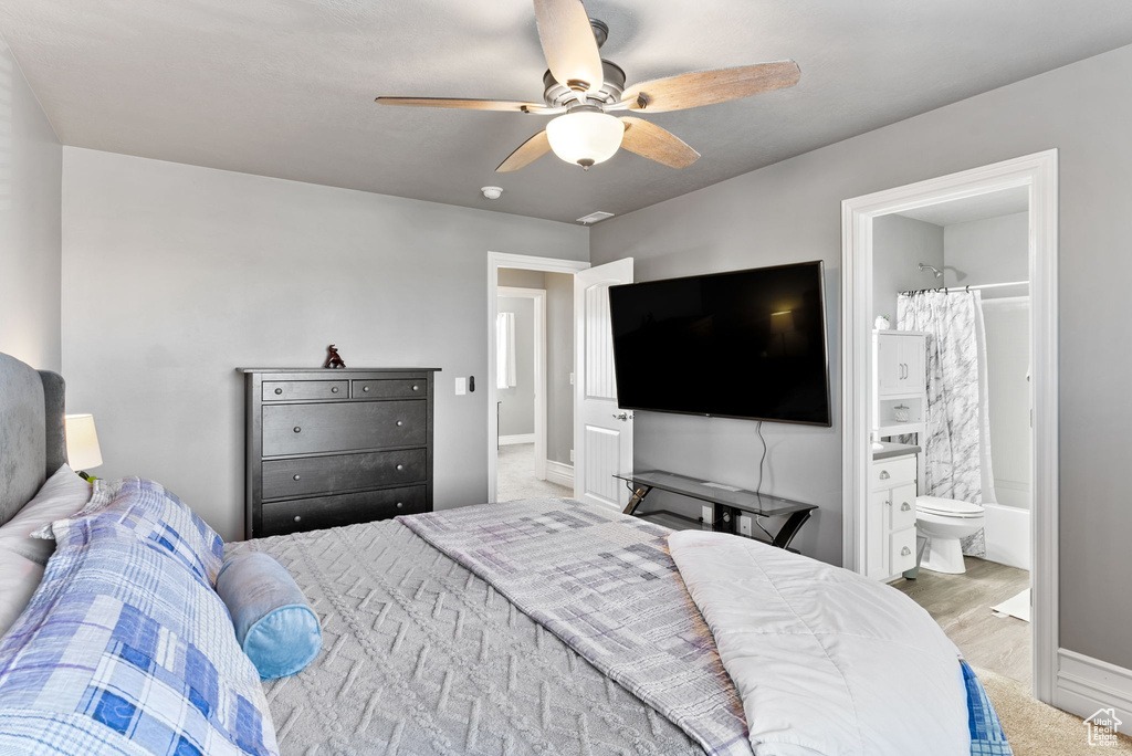 Carpeted bedroom featuring ceiling fan and connected bathroom