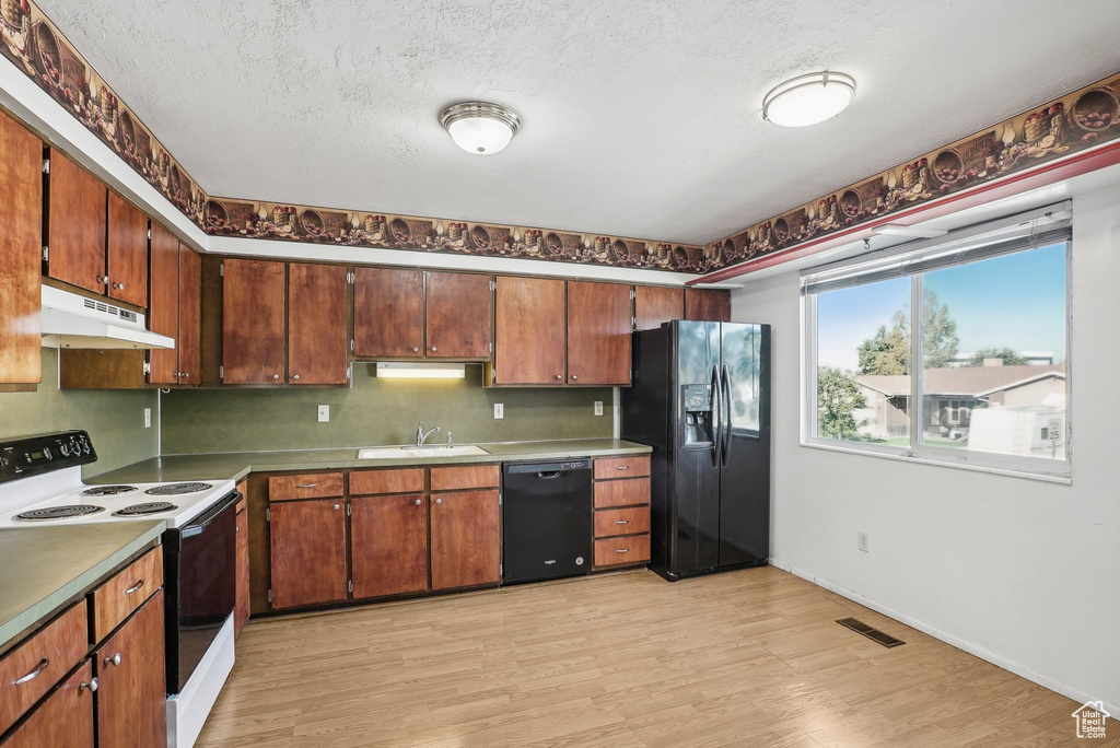 Kitchen featuring light hardwood / wood-style floors, a textured ceiling, black appliances, and sink