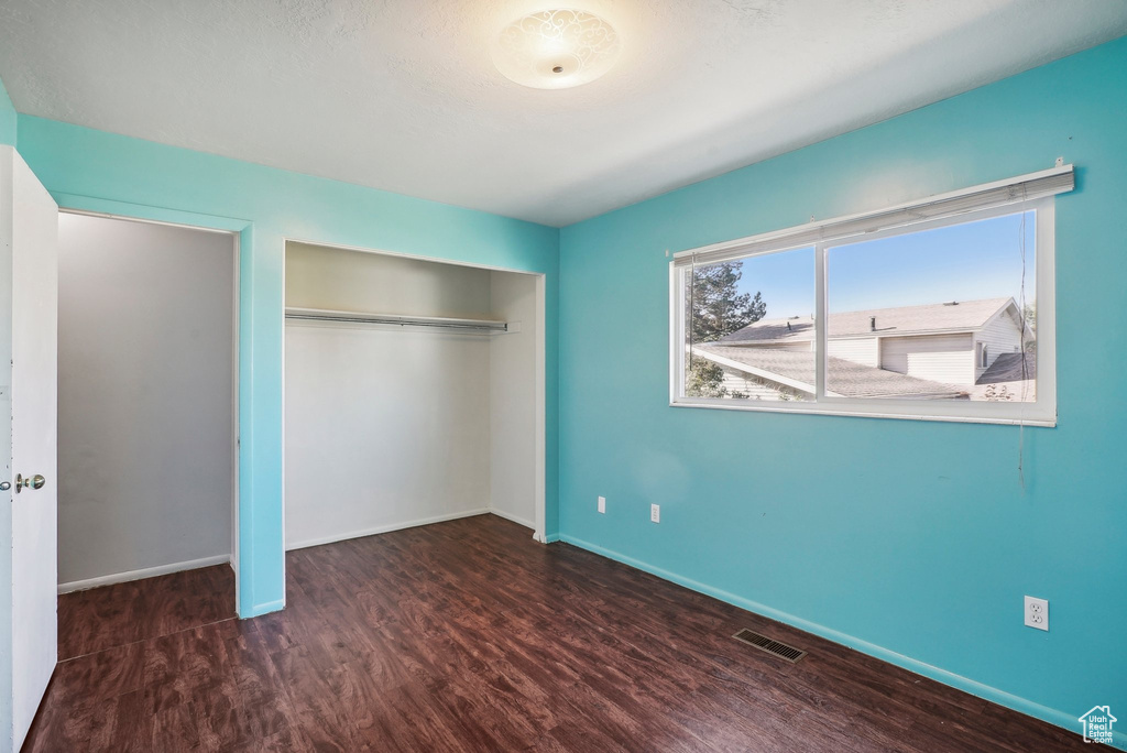 Unfurnished bedroom featuring a closet and dark hardwood / wood-style floors