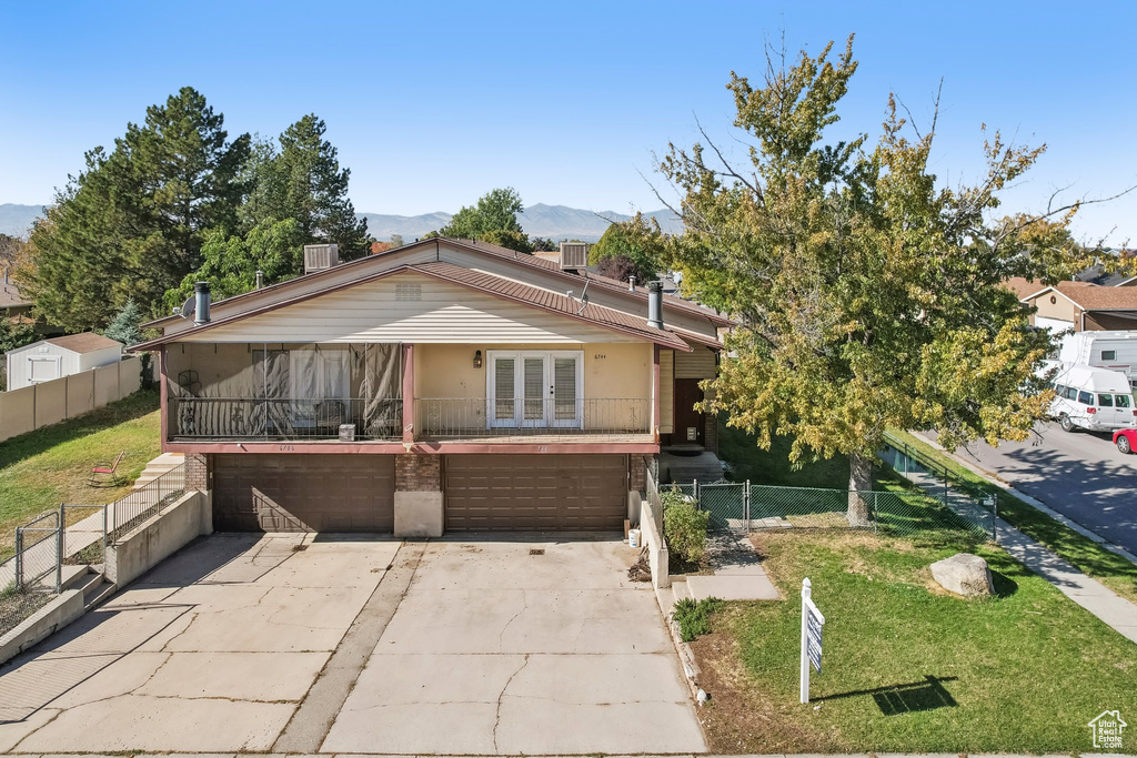 View of front of home with a front yard, a garage, and a mountain view