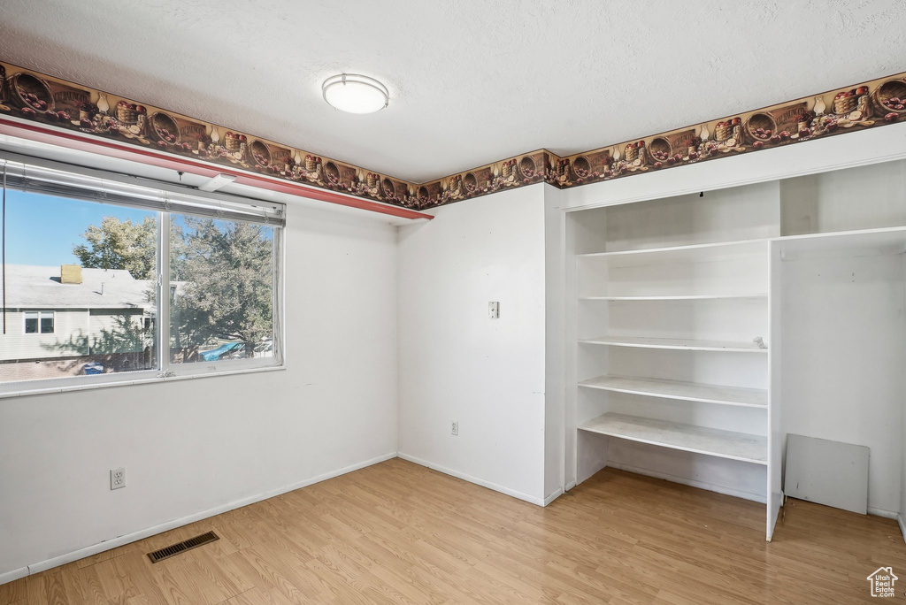 Unfurnished bedroom with hardwood / wood-style floors and a textured ceiling