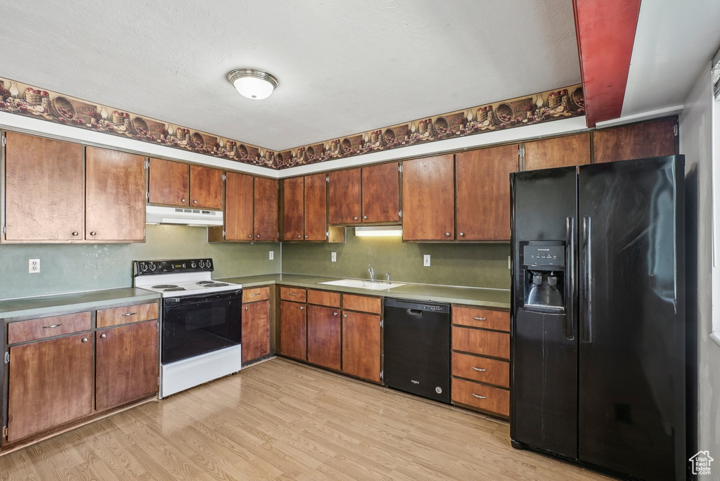 Kitchen with sink, black appliances, and light hardwood / wood-style flooring