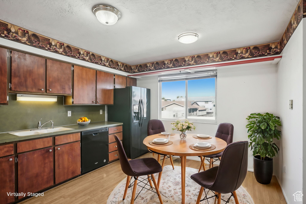 Kitchen featuring black dishwasher, a textured ceiling, refrigerator with ice dispenser, light hardwood / wood-style flooring, and sink