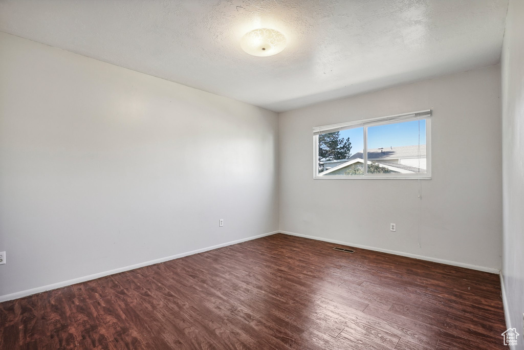 Spare room with a textured ceiling and dark hardwood / wood-style flooring