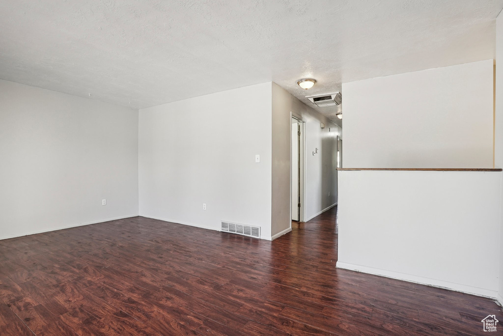 Unfurnished room featuring a textured ceiling and dark hardwood / wood-style floors