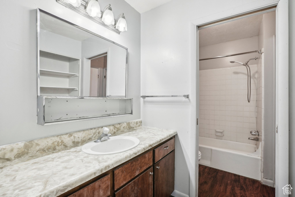 Full bathroom featuring vanity, hardwood / wood-style floors, tiled shower / bath combo, and toilet