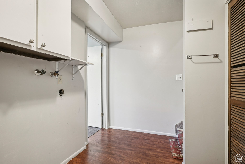 Clothes washing area featuring dark hardwood / wood-style floors and cabinets