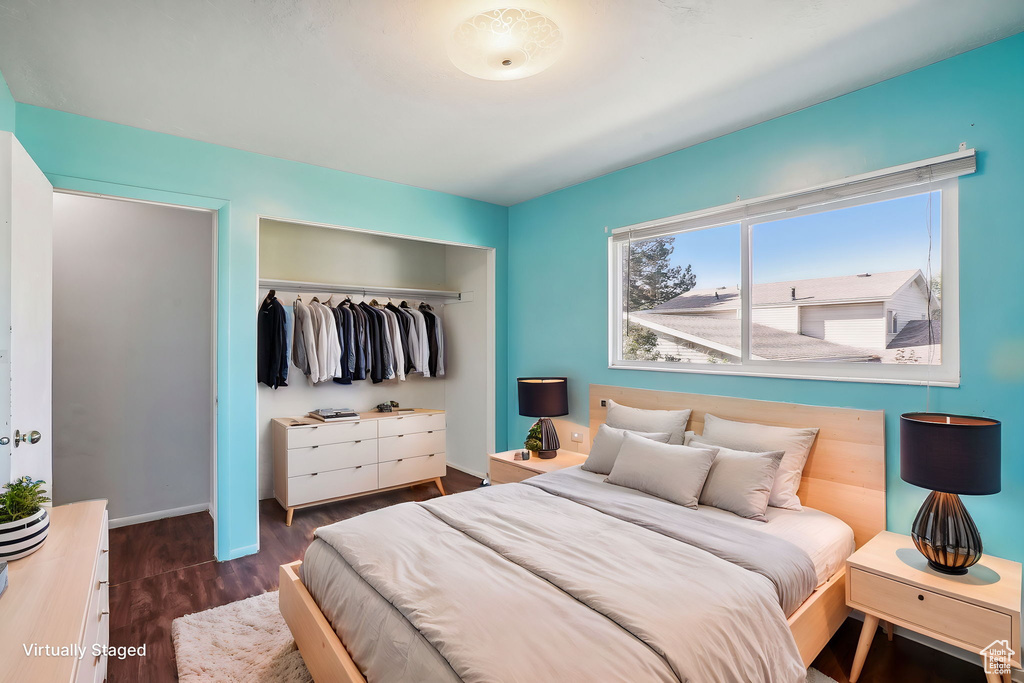 Bedroom with dark hardwood / wood-style floors and a closet