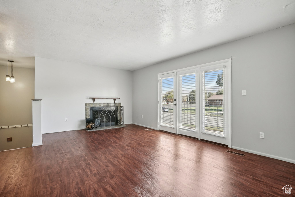 Unfurnished living room with a textured ceiling and dark wood-type flooring