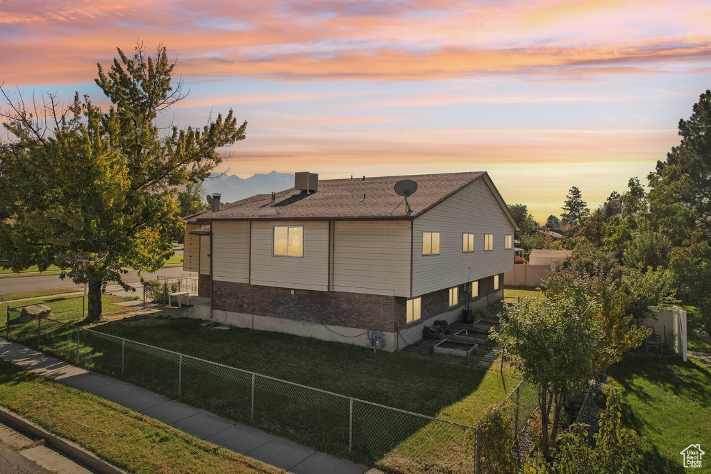 Property exterior at dusk featuring central AC and a lawn