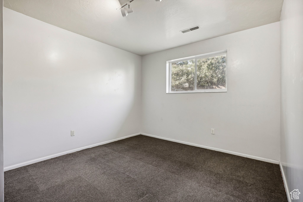 Spare room with track lighting and dark colored carpet