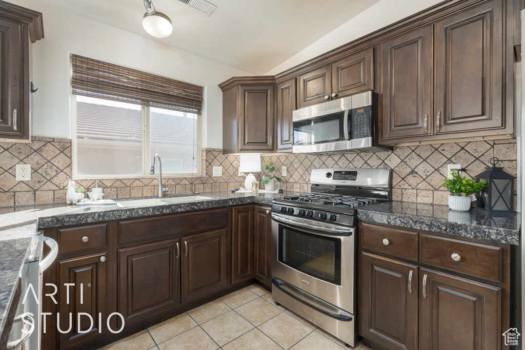 Kitchen with sink, decorative backsplash, light tile patterned flooring, and stainless steel appliances