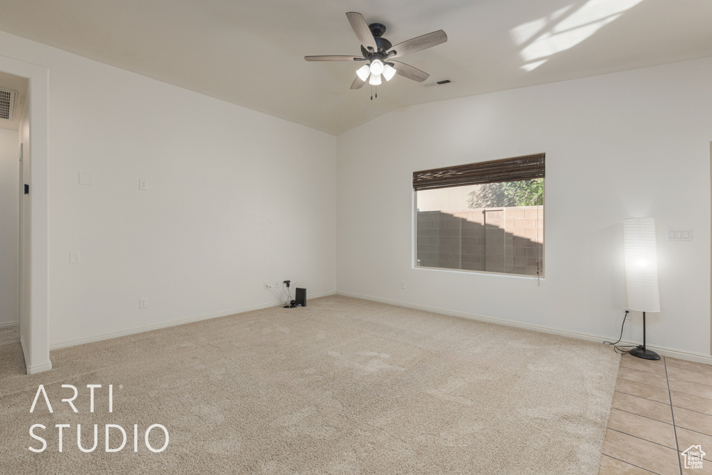 Empty room with vaulted ceiling, light colored carpet, and ceiling fan