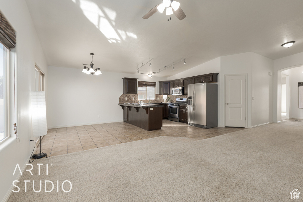 Kitchen featuring a healthy amount of sunlight, a kitchen breakfast bar, appliances with stainless steel finishes, and a kitchen island