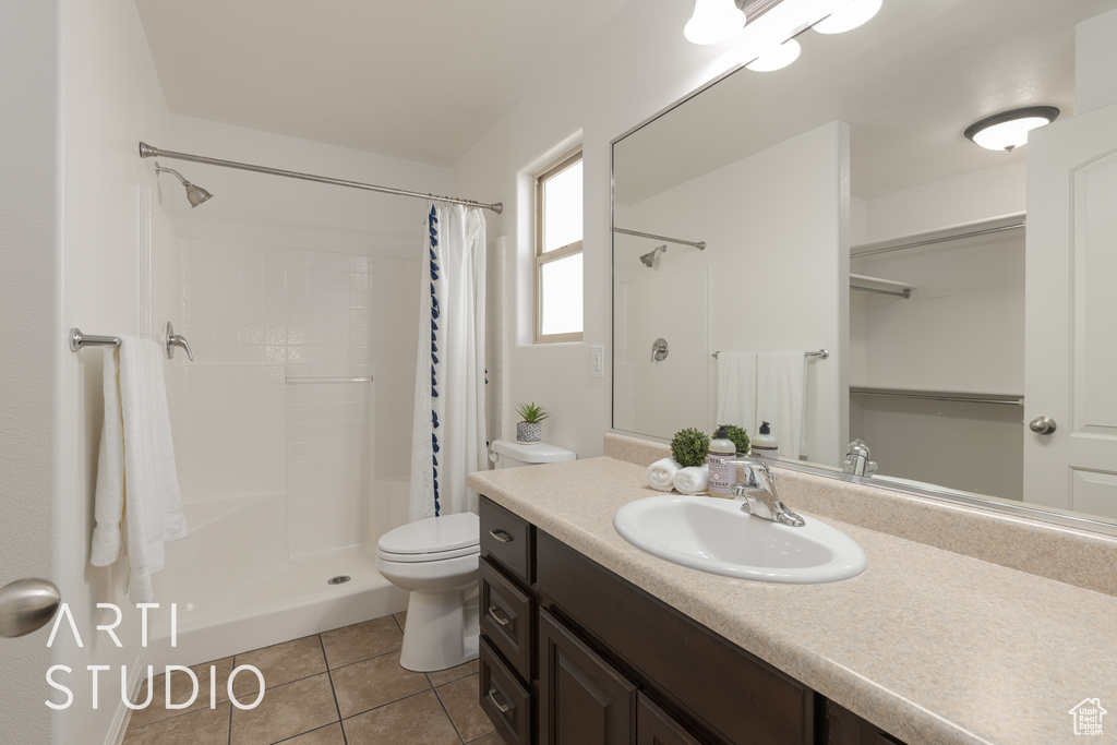 Bathroom with toilet, a shower with curtain, vanity, and tile patterned flooring