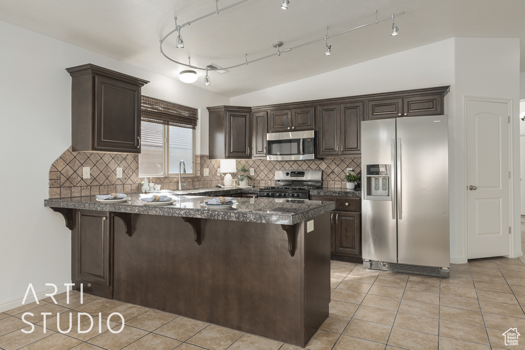 Kitchen with a breakfast bar, decorative backsplash, stainless steel appliances, and kitchen peninsula