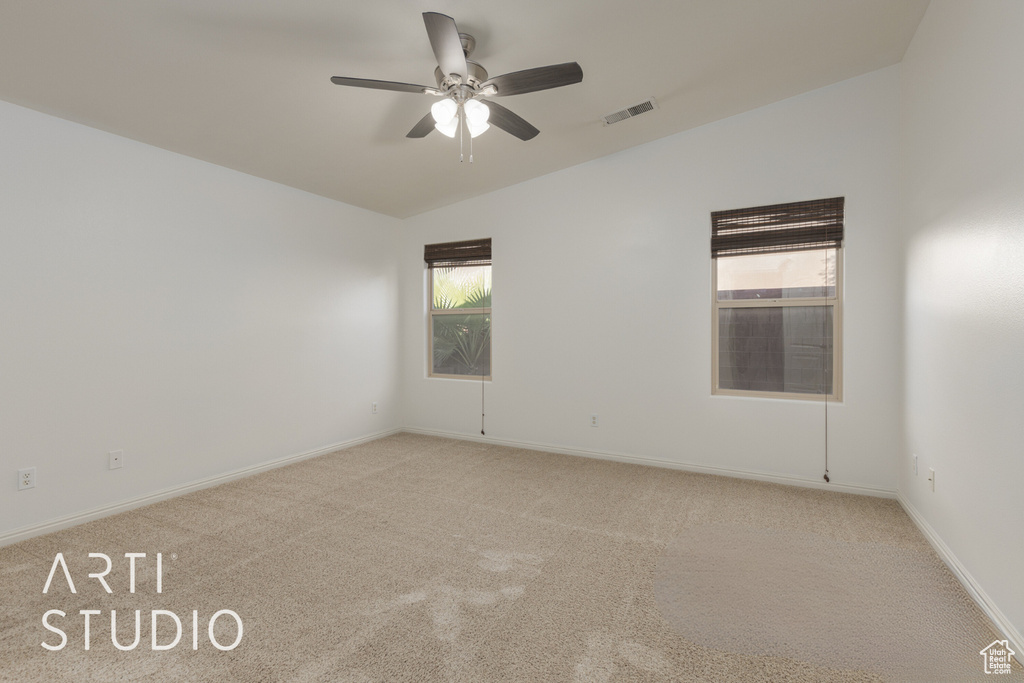 Carpeted empty room featuring lofted ceiling, ceiling fan, and a wealth of natural light